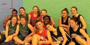Rocío en el centro con camiseta roja, sonríe en una fotografía con su equipo de baloncesto de la Universidad.