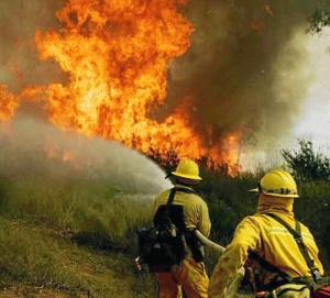 Dos bomberos apagan un incendio.