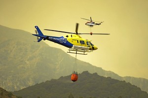 Imagen de dos helicópteros recogiendo agua para la extinción de incendios en Andalucía.